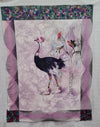 Fabric panel with Ostrich with rainbow coloured baseball cap, stockings and basketball shoes with a background of etched palm tree three rainbow coloured small birds on a mauve white stencilled leaf sides edged with spirals of pink and black top has blocks of flying geese in batik with leaves bottom corners have cerise leaves and bubbles