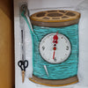 Ceramic Novelty Clock in shape of cotton reel with needle in browns teal second hand as scissors